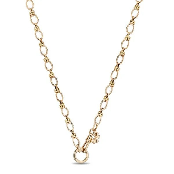 A delicate gold chain necklace with a small clover charm and a hanging ring pendant, displayed against a solid white background.