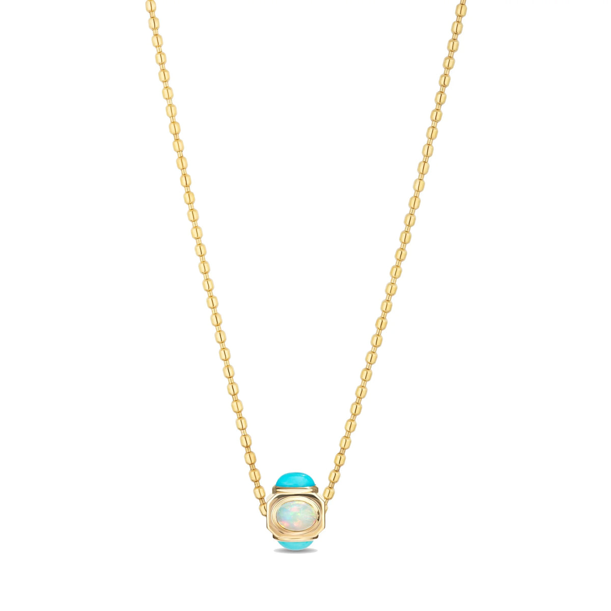 A gold chain necklace featuring a small oval pendant with a light blue cabochon stone and a central iridescent white opal-like inlay, set against a plain white background.