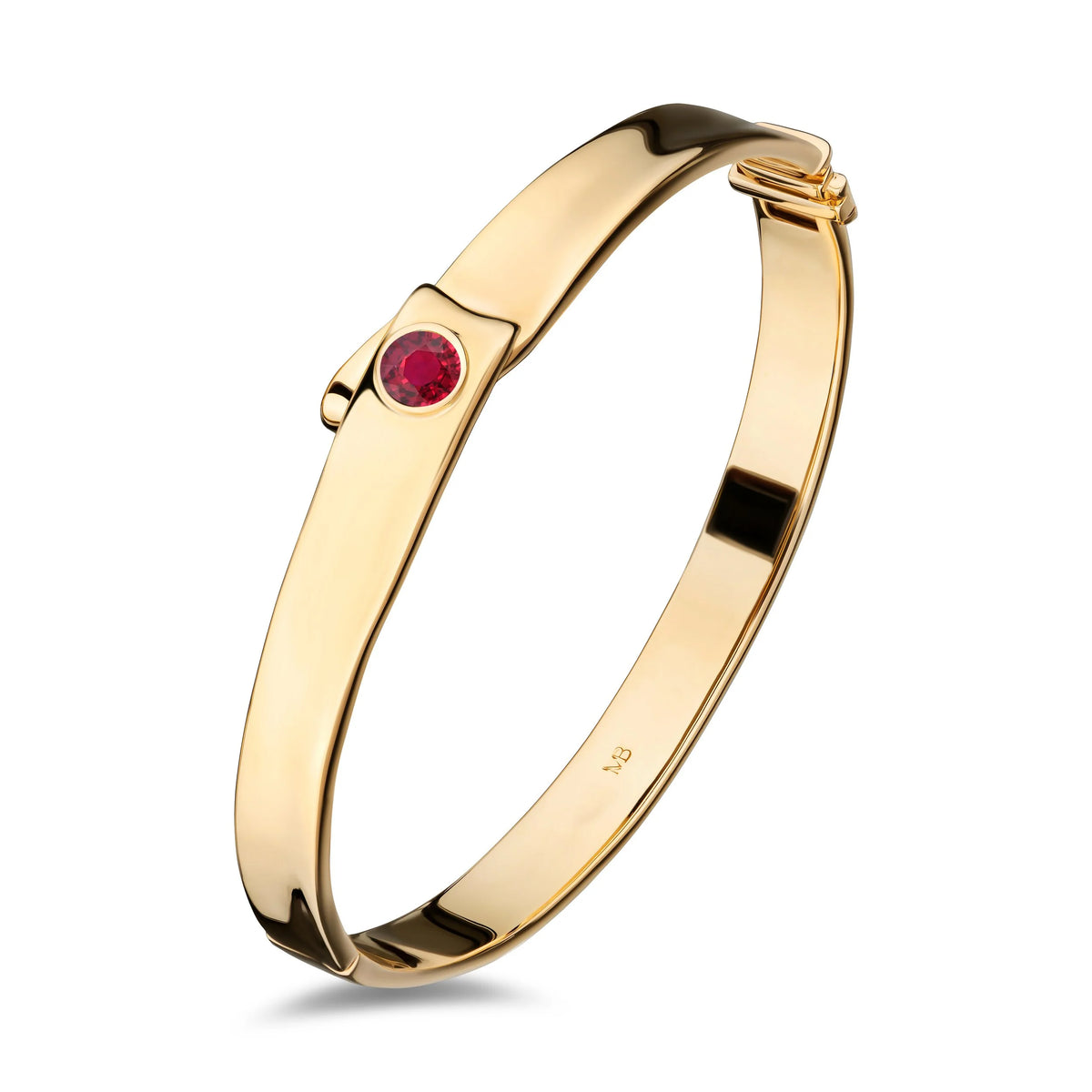 A polished yellow gold bangle bracelet with a single round red gemstone accent on the front, displayed on a clean white background.
