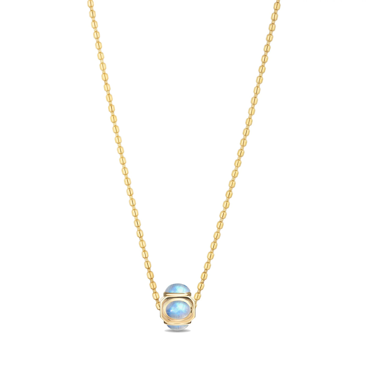 A delicate gold chain necklace featuring a small oval pendant with a light blue iridescent opal in a gold bezel setting, shown against a plain white background.