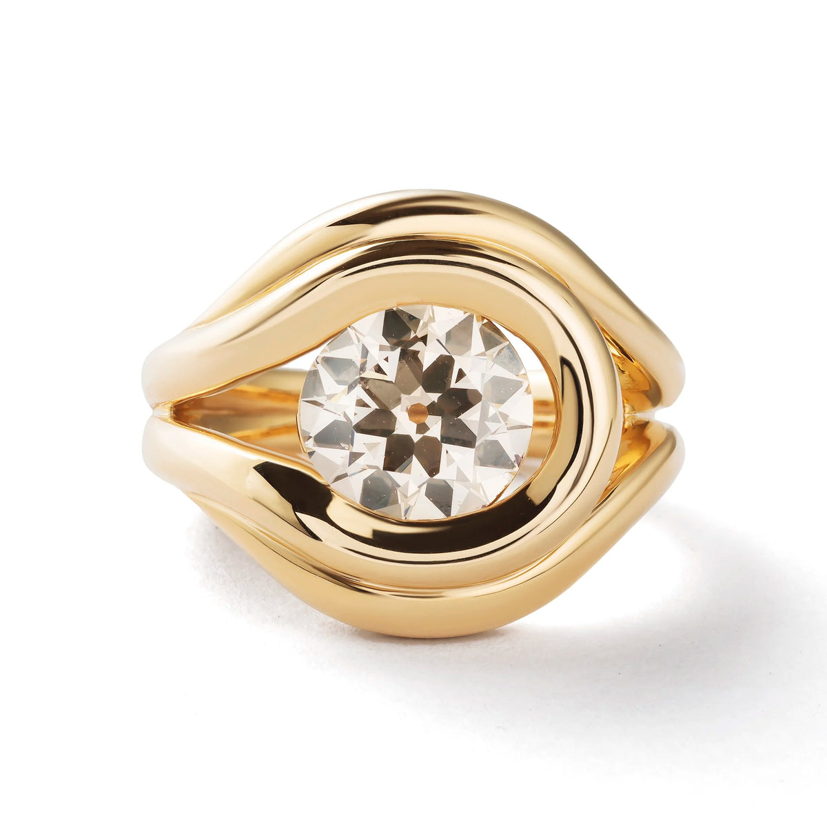 A gold ring with a large, round, clear central gemstone, featuring a polished wavy band design on a white background.