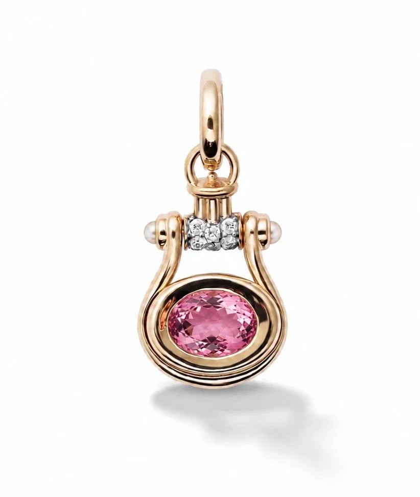 A gold and pink gemstone pendant featuring a central oval pink stone, a small row of clear stones above, and delicate curved gold wire details, shown on a white background.