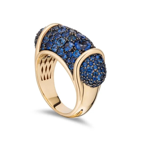 A yellow gold ring featuring a wide, curved pavé setting with deep blue sapphires, shown on a clean white background.