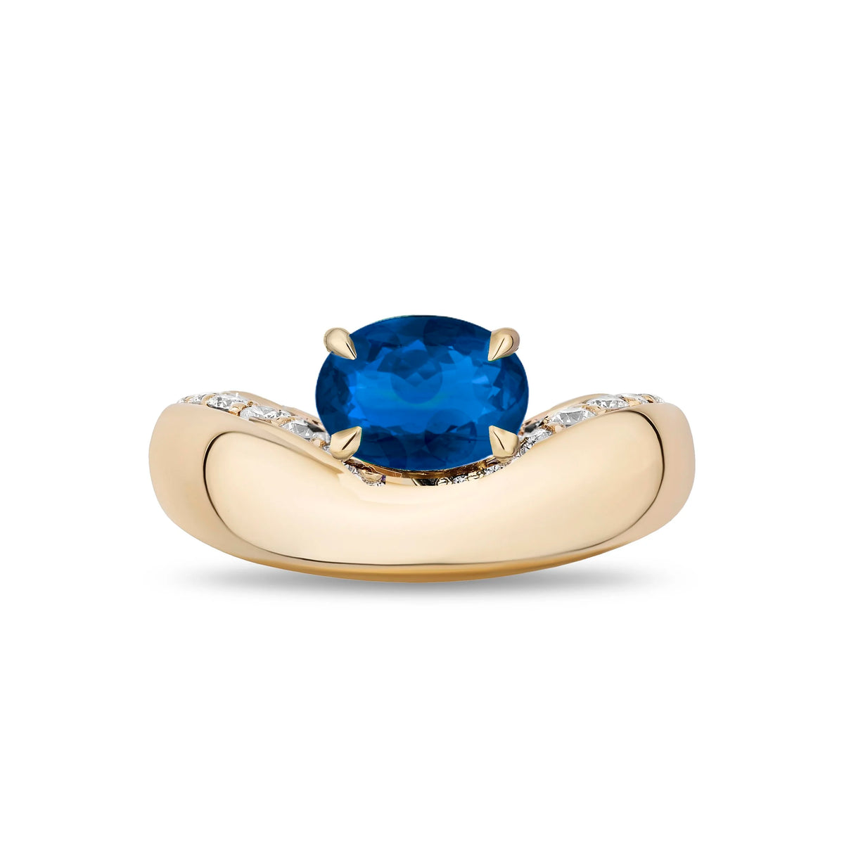 A yellow gold ring featuring a large oval-cut blue sapphire center stone, with small pavé-set clear stones along the shoulders of a curved band, shown on a plain white background.